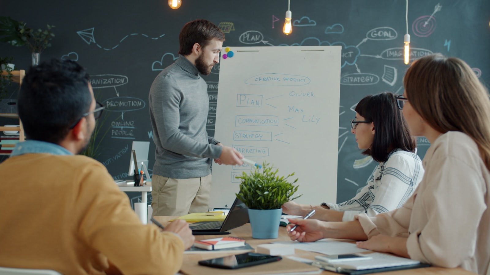A marketing team gathered around a whiteboard sketching a content calendar in a modern office