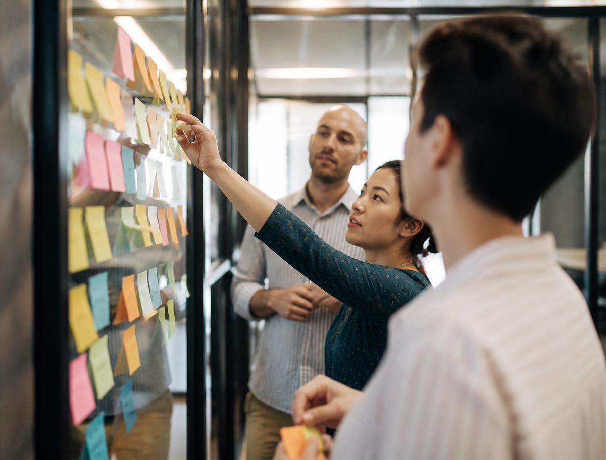 A team clustering sticky notes of customer questions into groups on a glass wall