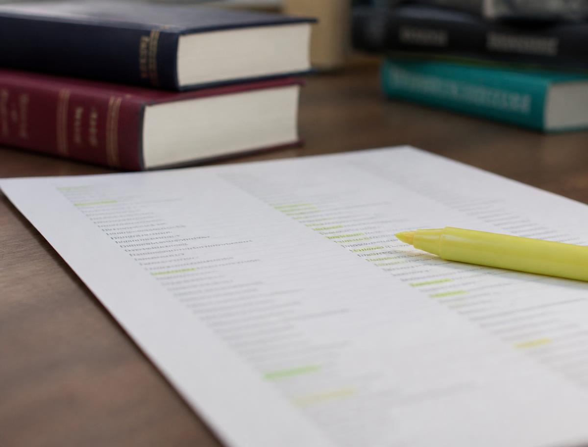 A printed glossary of terms marked with a highlighter, reference books nearby