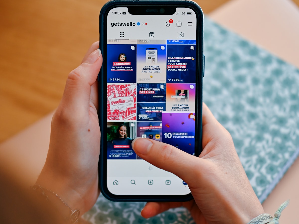 A pair of hands holding a phone scrolling a social media feed