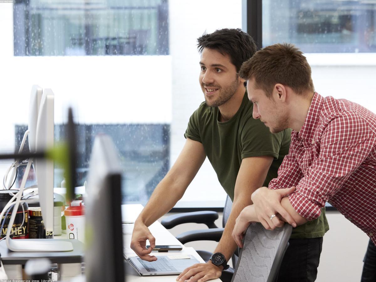 An analyst cross-referencing a company record against a source website on a second monitor