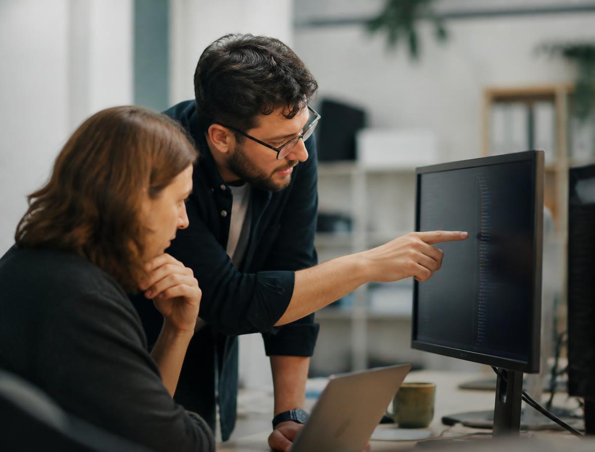 Two coworkers troubleshooting a broken step at a monitor