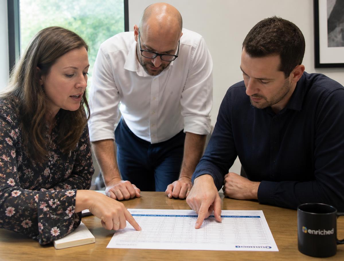 A small team reviewing a printed sample of enriched records at a table