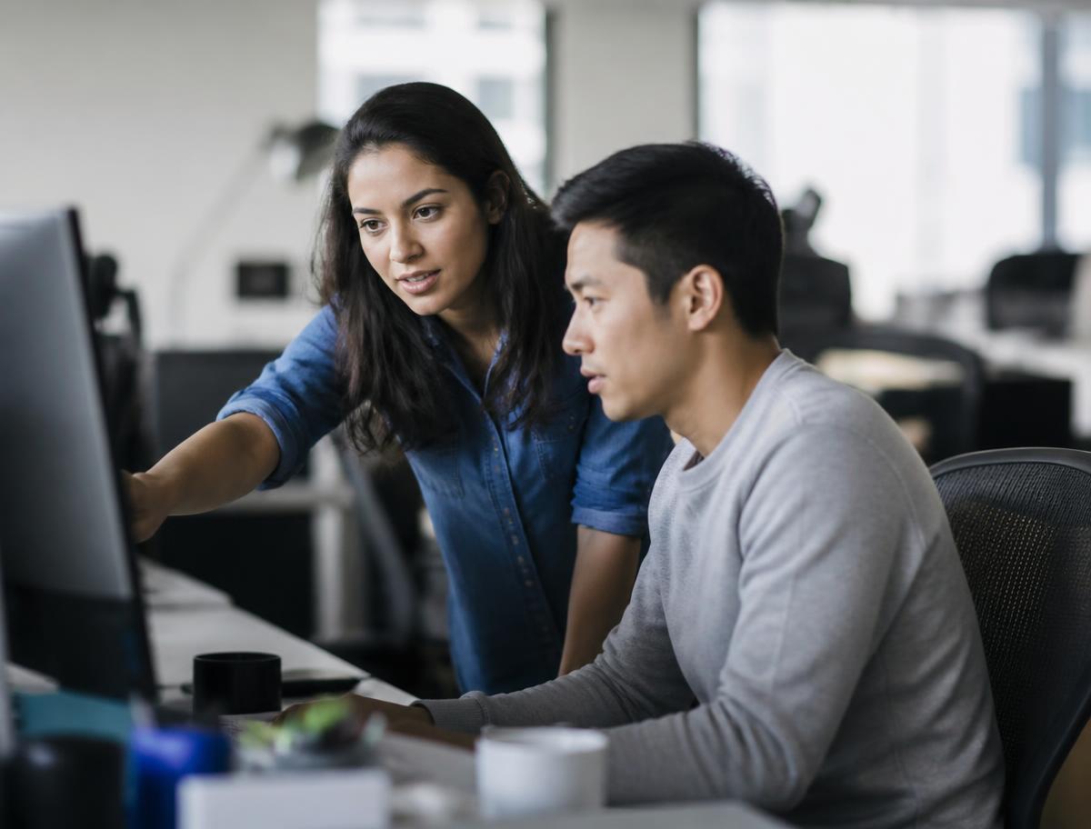 A colleague showing a new internal tool to a coworker at their desk
