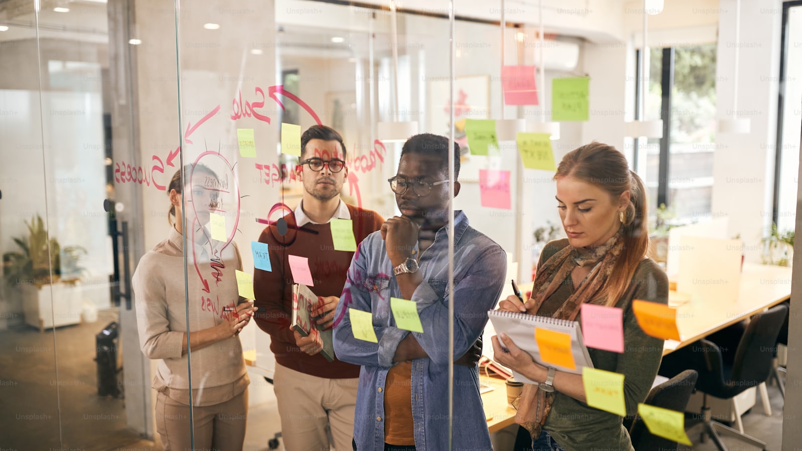 A marketing team reviewing a mind map of campaign ideas on a glass wall in the office