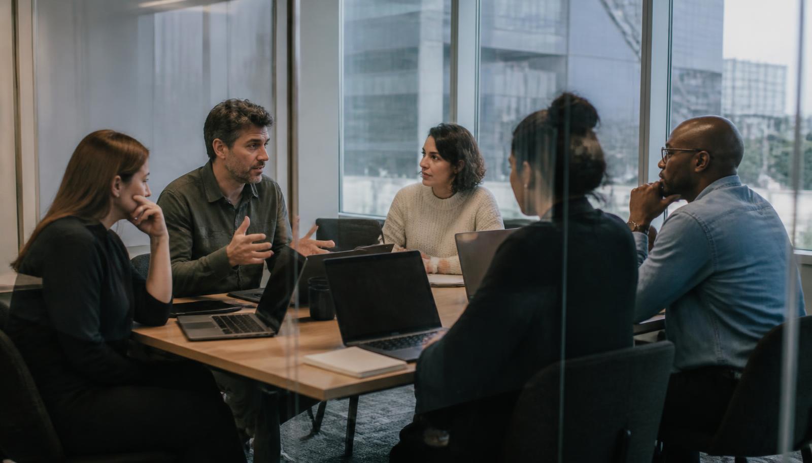 A weekly pipeline review meeting in a glass-walled room