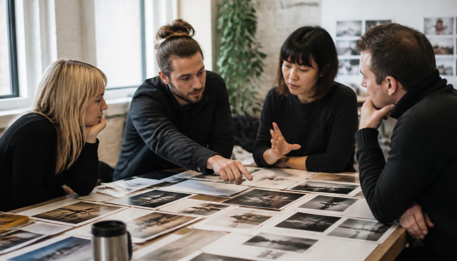 Four people around a table comparing printed outputs and debating which is better