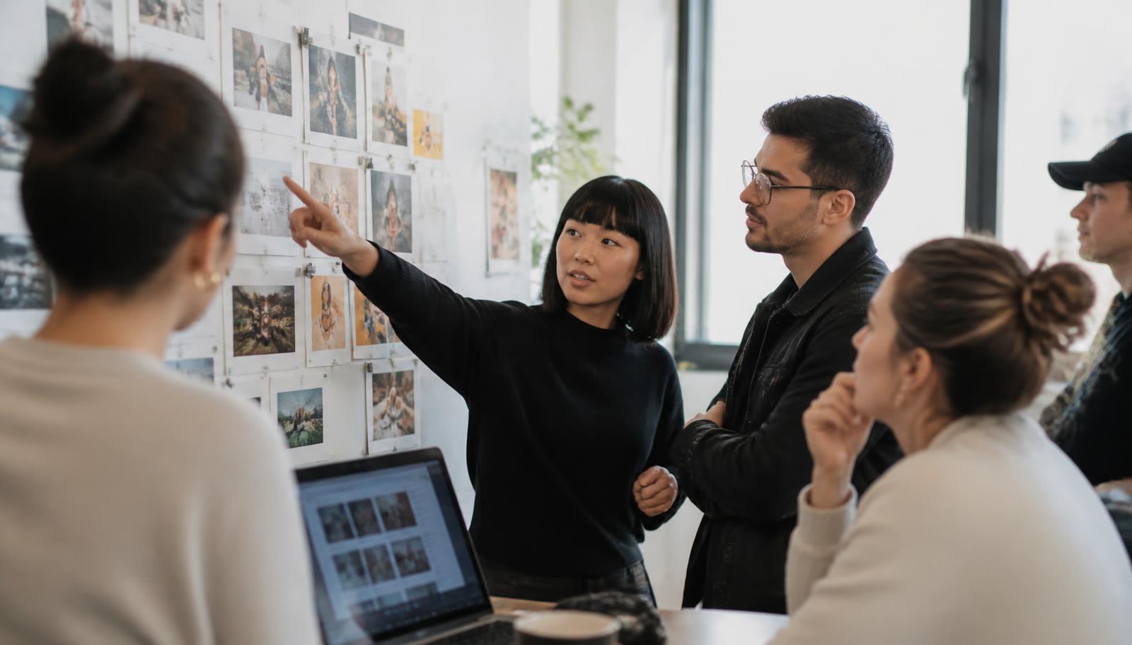 A small content team reviewing printed social posts pinned to a studio wall